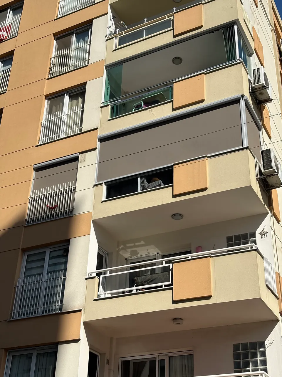 İzmir'de aynı apartmanda üst katta cam balkon, altında köşe dönen balkon zip perde ve en altta açık balkon