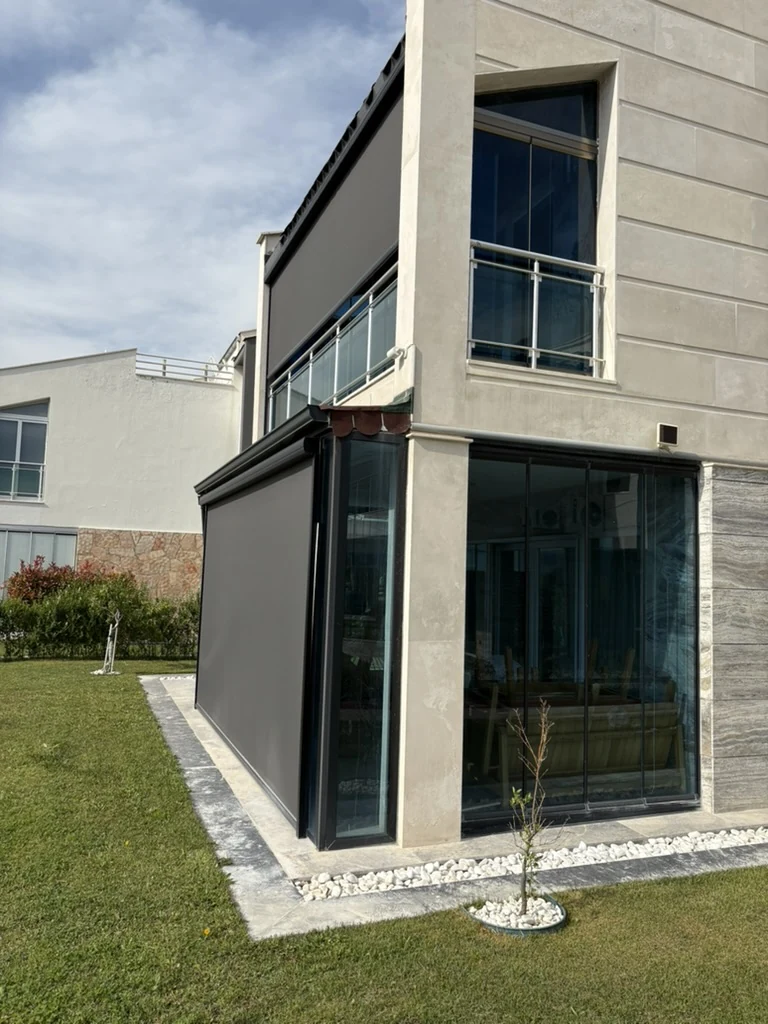 Cam ile kapatılmış bahçe katı alanının dışına uygulanmış antrasit zip perde